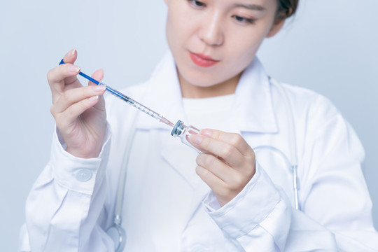女醫(yī)生手持疫苗瓶和注射器特寫