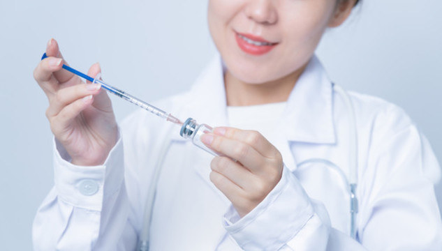 醫(yī)生手持疫苗瓶和注射器特寫