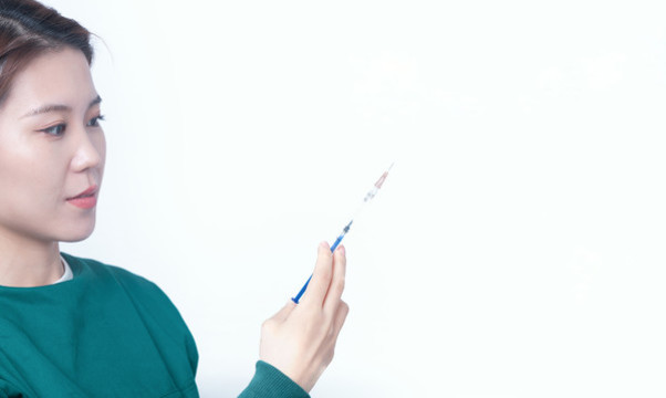 手術(shù)服手持注射器的女性