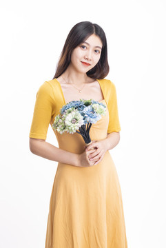 穿黃色連衣裙拿著一束花的女人