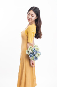 穿黃色連衣裙拿著一束花的女人
