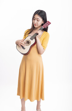 穿著連衣裙拿著尤克里里的女人