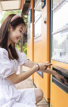 在自動(dòng)售賣機(jī)旁取貨的美麗女孩
