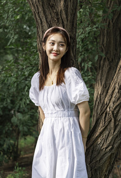 森林里靠在大樹上的美麗女孩