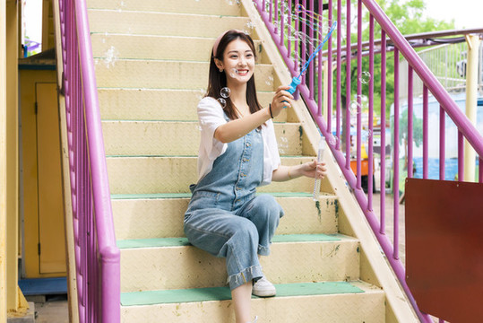 在游樂園里玩吹泡泡的美麗女孩