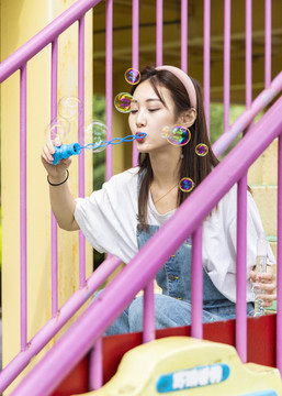 在游樂(lè)園里玩吹泡泡的美麗女孩