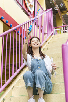 在游樂園里玩吹泡泡的美麗女孩