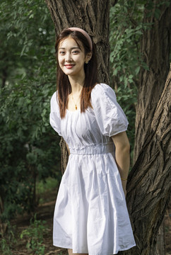 森林里靠在大樹上的美麗女孩