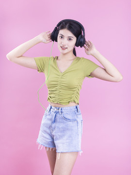 粉色背景里戴著耳機(jī)的亞洲美女