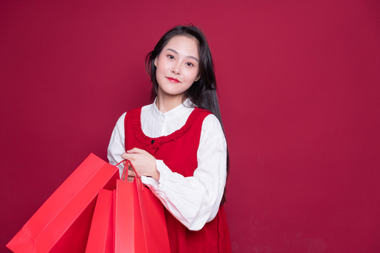 紅色背景前手提購(gòu)物袋的女性