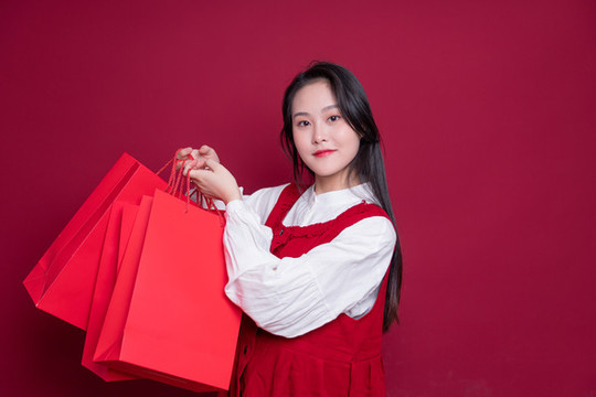 紅色背景前手提購(gòu)物袋的女性