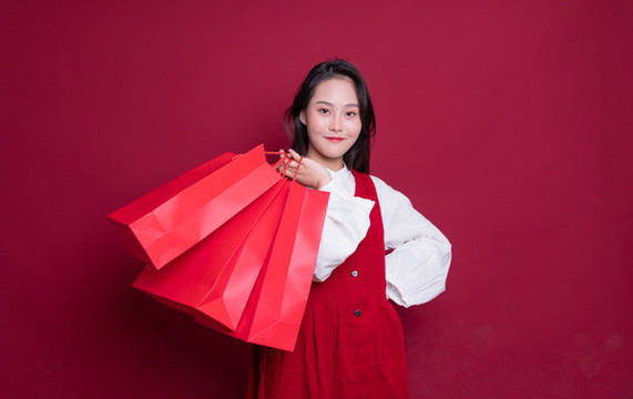 紅色背景前手提購(gòu)物袋的女性