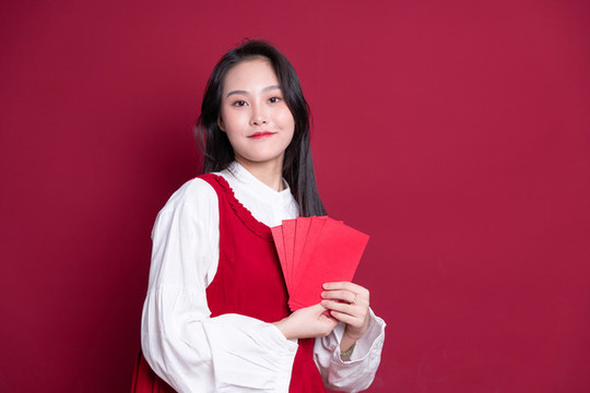 紅色背景前手持紅包的女孩