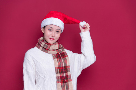 紅背景前帶著圣誕帽的女性