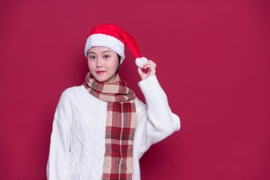 紅背景前帶著圣誕帽的女性