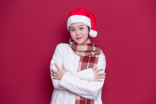 紅背景前帶著圣誕帽的女性