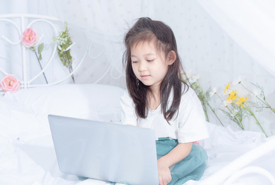 床上使用電腦的小女孩
