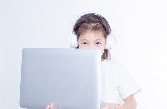 戴耳機(jī)使用電腦的小女孩