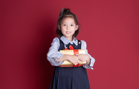 小女孩學(xué)生裝扮拿著禮物盒