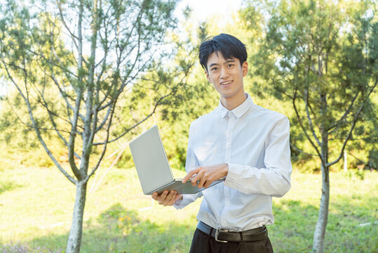 戶外拿著電腦的青年男性