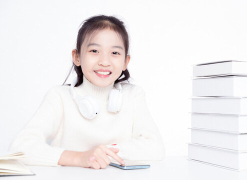 書桌上使用手機(jī)的小女孩