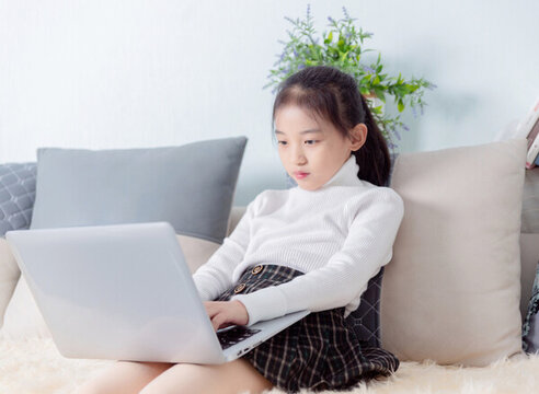 沙發(fā)上使用電腦的小女孩