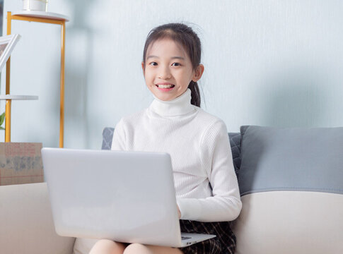 沙發(fā)上使用電腦的小學(xué)生