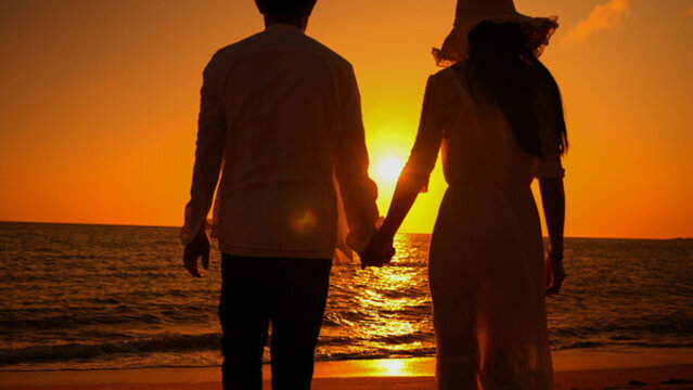 情侣在海边牵手看夕阳