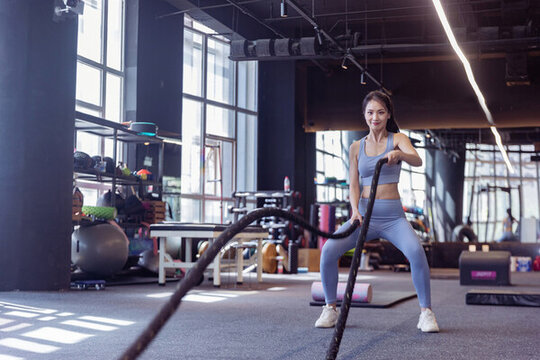 健身房年轻女性使用格斗绳锻炼
