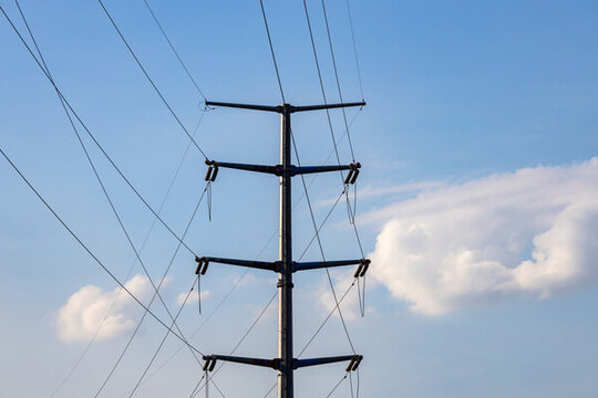 藍(lán)天白云背景前的供電輸電塔