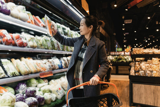 亚洲女性在超市的绿色食品挑选