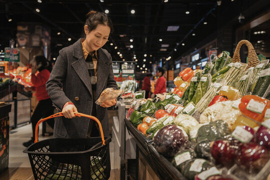 亚洲女性超级市场新鲜蔬菜的挑选