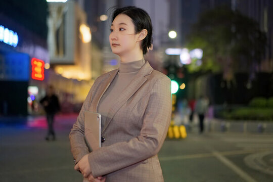行走在城市景觀夜色中的自信女性