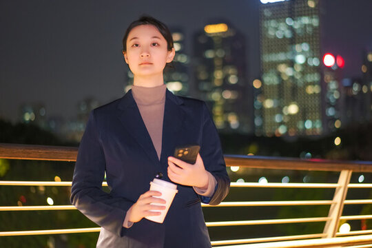 在城市燈光下拿著智能手機(jī)的女性