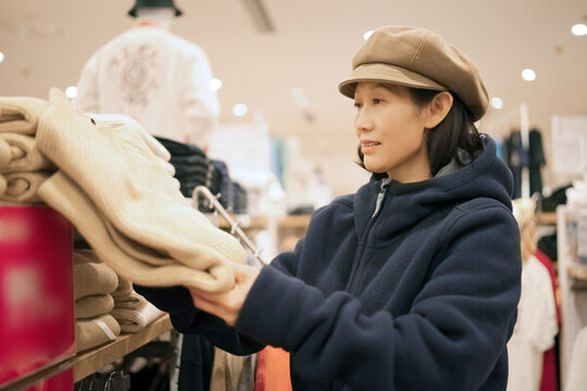 在商場貨架前挑選衣服購物的女性