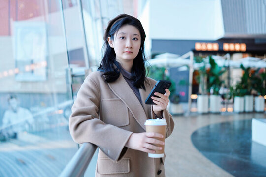 年輕女性在商場(chǎng)手持智能手機(jī)