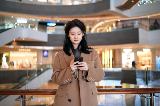 年輕女性在商場專注手機(jī)發(fā)短信