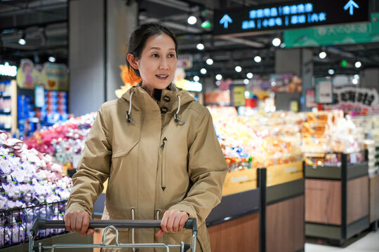 在超市推著購物車的女性