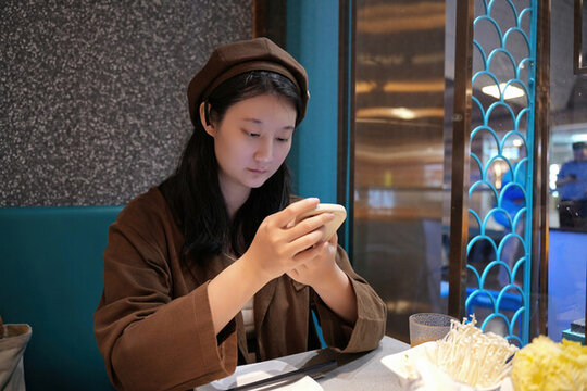 年輕女子在餐廳用智能手機雕刻