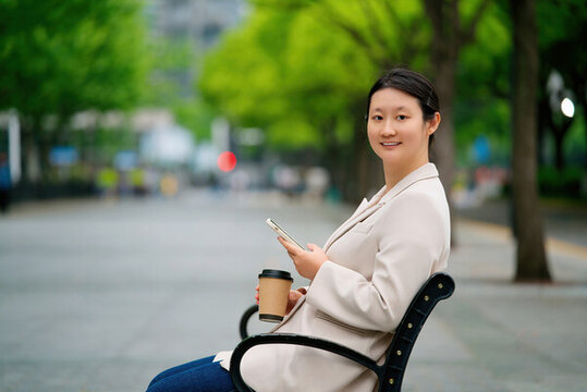 職業(yè)女性在公園長椅上咖啡休息