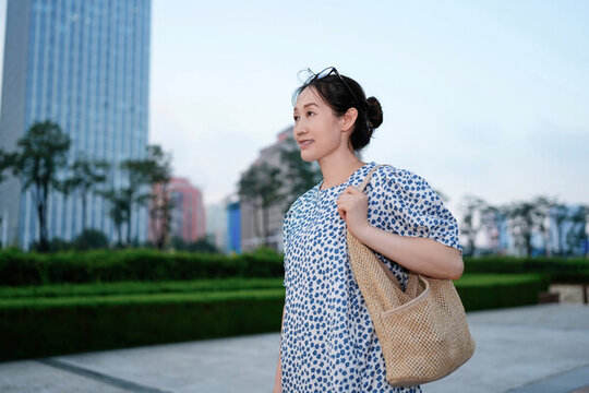 辦公樓外肩背包包的年輕女性