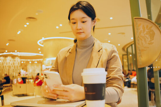職業(yè)女性在室內(nèi)喝咖啡查看手機(jī)