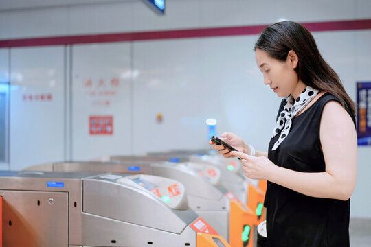 女性用手機在地鐵旋閘機中導航