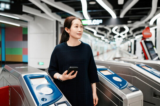女子在現(xiàn)代地鐵站用智能手機通勤