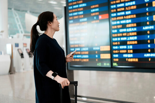 女子在現(xiàn)代機場航站樓查詢航班信息