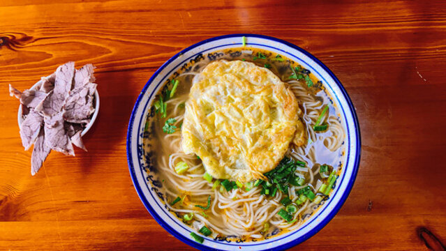 煎蛋面條配肉片美食圖