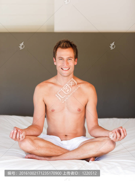 微笑的男人在床上做瑜伽