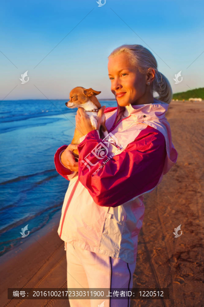 年輕的女人和她的狗在海灘上