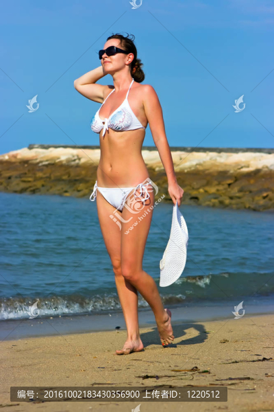 在海灘上戴著白帽子的女士