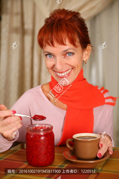 微笑的女人拿著一杯覆盆子果醬的茶
